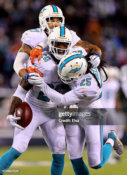 Reshad Jones of the Miami Dolphins celebrates with Louis Delmas and Jimmy Wilson after intercepting a ball intended for Jeff Cumberland of the New...