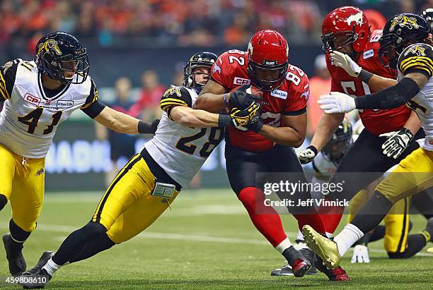 Craig Butler of the Hamilton Tiger-Cats tackles Nik Lewis of the Calgary Stampeders during the 102nd Grey Cup Championship Game at BC Place November...