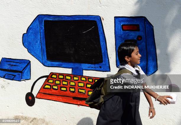 An Indian schoolgirl walks past a mural adorning a municipal school wall in Mumbai on December 31, 2013. The Right to Education Act passed in 2009...