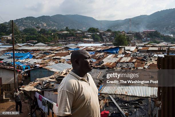 Andrew Kondoh prepares to pick up the body of a 7-month old baby in Race Course area of Freetown, Sierra Leone, on Sunday, November 23, 2014.