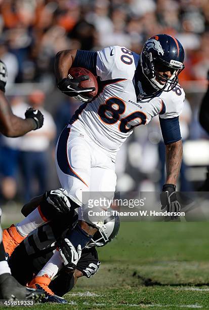 Julius Thomas of the Denver Broncos gets tackled by Phillip Adams of the Oakland Raiders during the second quarter at O.co Coliseum on December 29,...