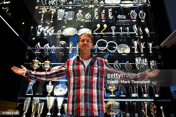 Sebastian Vettel of Germany poses next to the Infiniti red Bull Racing trophy cabinet during a visit to the Red Bull Racing Factory on December 2,...