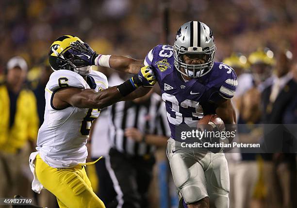 Running back John Hubert of the Kansas State Wildcats stiff arms defensive back Raymon Taylor of the Michigan Wolverines as he rushes the football...