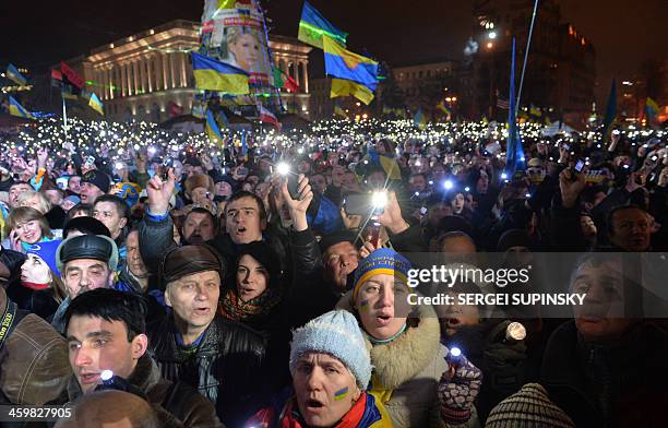Ukrainians light electric torches and the phones as they sing the state anthem during a mass demonstration marking the New Year on Independence...