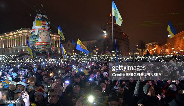 Ukrainians light electric torches and phones as they sing the state anthem during a mass demonstration marking the New Year on Independence Square in...