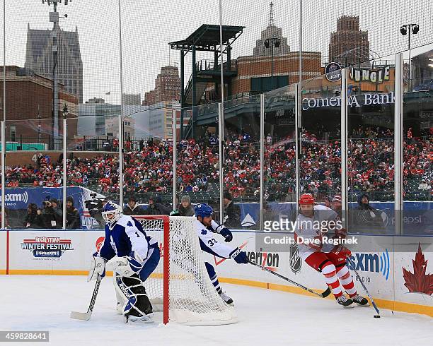 Jimmy Carson of the Detroit Red Wings Alumni skates with the puck around Matt Martin and Peter Ing of the Toronto Maple Leafs Alumni during the 2014...