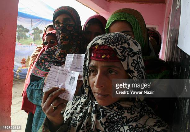 Kashmiri woman wait in queue to cast their votes outside a polling station during the second phase of assembly elections on December 02, 2014 in...