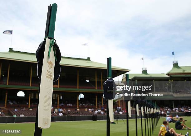 Cricket bats with Phillip Hughes' milestones are displayed on the SCG field as people gather to watch the funeral service held in Macksville for...