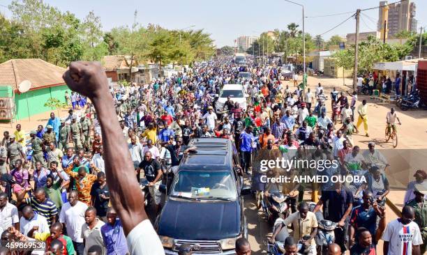 Man holds up his fist as people attend the official funeral of "martyrs" of the uprising that ousted president Blaise Compaore, at Revolution Square...