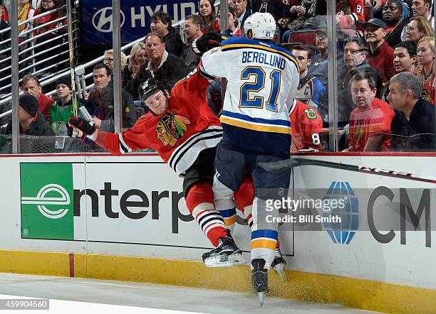 Bryan Bickell of the Chicago Blackhawks is checked by Patrik Berglund of the St. Louis Blues during the NHL game at the United Center on December 3,...