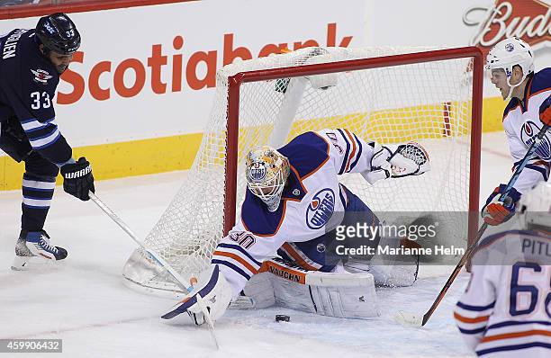 Ben Scrivens of the Edmonton Oilers keeps the puck out of the net as Dustin Byfuglien of the Winnipeg Jets tries to score in first-period action in...