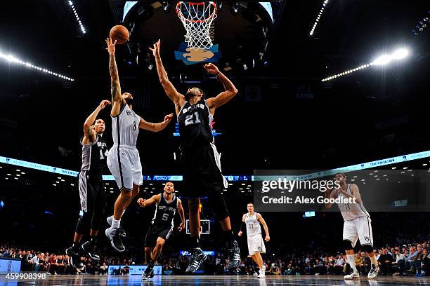 Deron Williams of the Brooklyn Nets attempts a shot over Tim Duncan of the San Antonio Spurs in overtime at the Barclays Center on December 3, 2014...