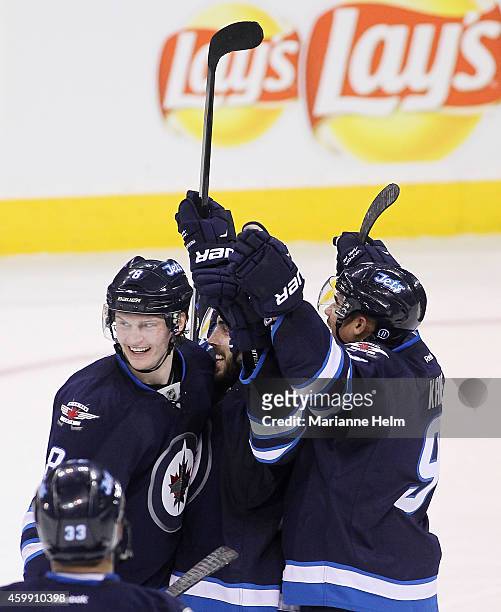 Mathieu Perreault of the Winnipeg Jets celebrates his game-winning goal with teammates Jacob Trouba and Evander Kane in overtime action in an NHL...
