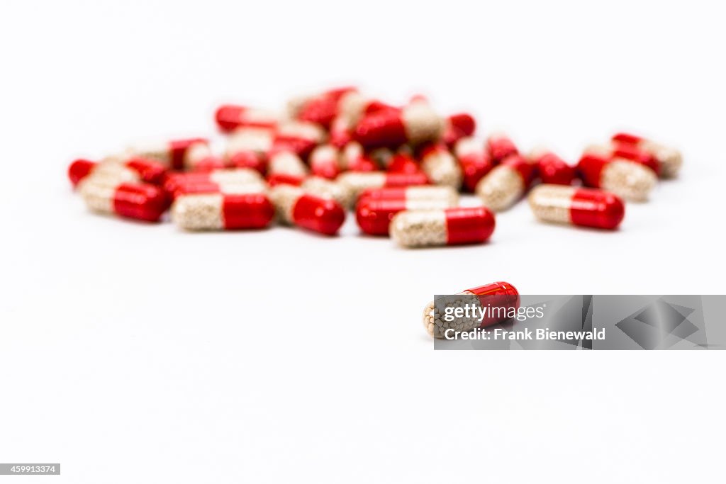 Many red and transparent medical capsules, filled with...