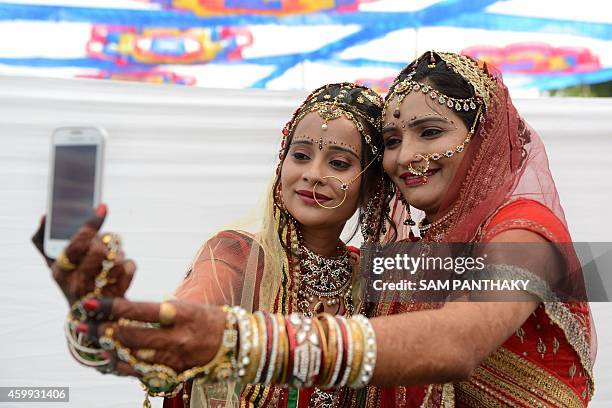 Indian sisters and brides from the Rabari Samaj community, Rupal Desai and Rinku Desai take a 'selfie' photograph on a mobile phone before...