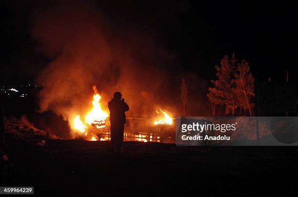 Pakistani man stands near a burning bus following a suicide attack in Quetta on January 01, 2014. At least two people were killed, and 20 injured,...