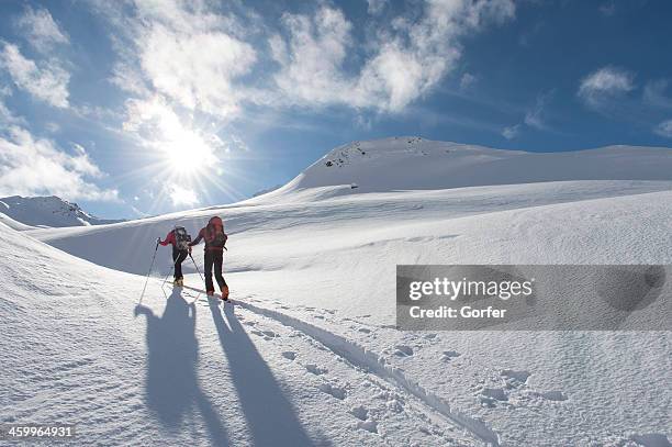 ski touring trails - team climbing up to mountain top stockfoto's en -beelden