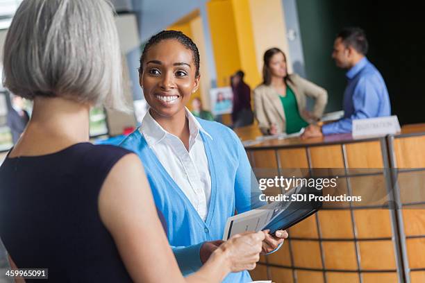 women exchanging resumes at professional job fair event - job fair stock pictures, royalty-free photos & images