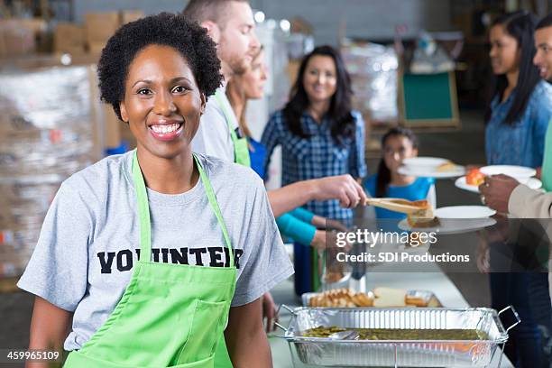 african american woman volunteering at community soup kitchen - soup kitchen stock pictures, royalty-free photos & images