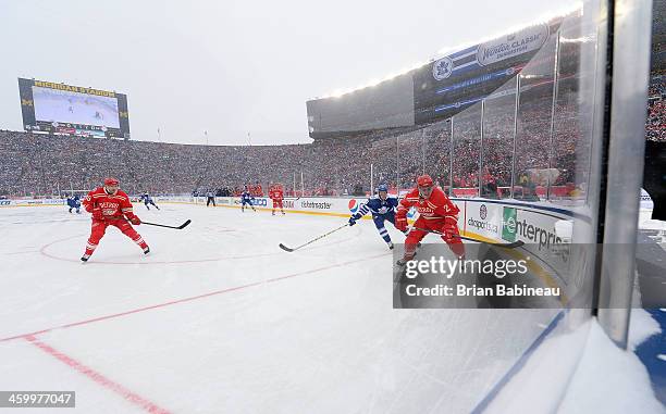 Brendan Smith of the Detroit Red Wings skates after the puck while under pressure from James van Riemsdyk of the Toronto Maple Leafs as Pavel Datsyuk...