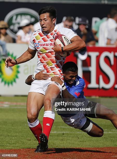 Reupena Levasa of Samoa tackles Yoshiaki Tsurugasaki of Japan during their rugby match on the first day of the Dubai leg of IRB's Sevens World Series...