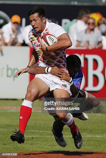 Reupena Levasa of Samoa tackles Yoshiaki Tsurugasaki of Japan during their rugby match on the first day of the Dubai leg of IRB's Sevens World Series...