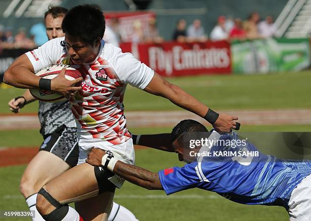 Tom Losefo of Samoa tackles Kazushi Hano of Japan during their rugby match on the first day of the Dubai leg of IRB's Sevens World Series on December...