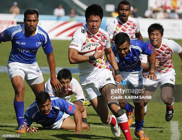 Kazushi Hano of Japan runs with the ball followed by Tom Losefo of Samoa during their rugby match on the first day of the Dubai leg of IRB's Sevens...