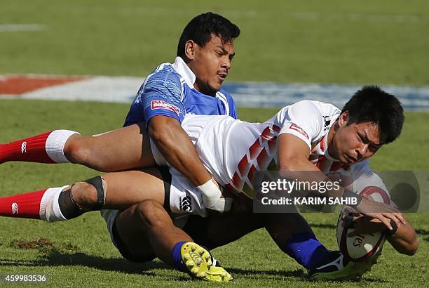 Tom Losefo of Samoa tackles Kazushi Hano of Japan during their rugby match on the first day of the Dubai leg of IRB's Sevens World Series on December...