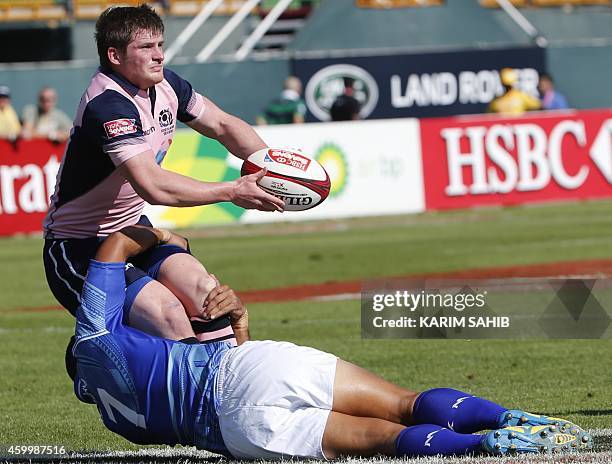 James Johnstone of Scotland passes the ball as he is tackled by Lolo Lui of Samoa during their rugby match on the first day of the Dubai leg of IRB's...