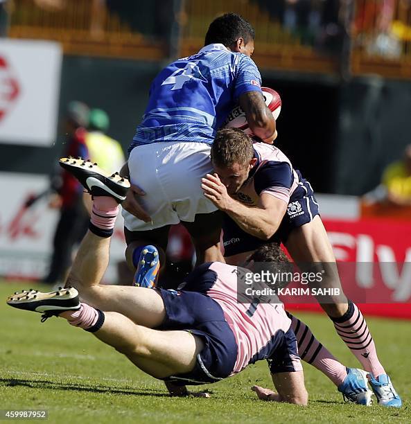 Scott Riddell and Nyle Nayacvou of Scotland tackle Fale So'oialo of Samoa during their rugby match on the first day of the Dubai leg of IRB's Sevens...