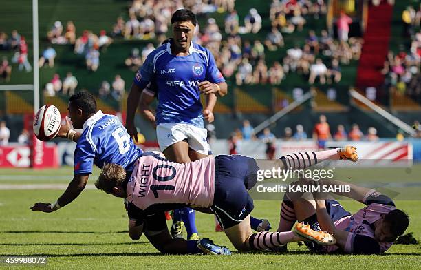 Colin Shaw and Scott Wight of Scotland tackle Tom Iosefo of Samoa during their rugby match on the first day of the Dubai leg of IRB's Sevens World...