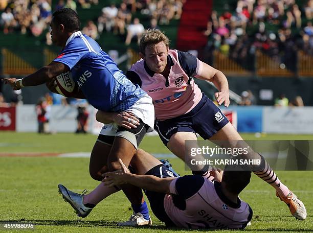 Colin Shaw and Scott Wight of Scotland tackle Tom Iosefo of Samoa during their rugby match on the first day of the Dubai leg of IRB's Sevens World...