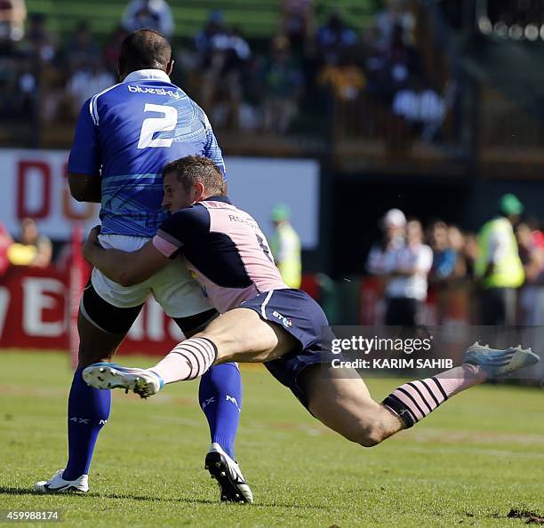 Mark Robertson of Scotland tackles Falemiga Selesele of Samoa during their rugby match on the first day of the Dubai leg of IRB's Sevens World Series...