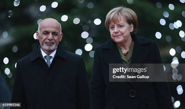 German Chancellor Angela Merkel and Afghan President Ashraf Ghani walk past a Chrismtas tree upon Ghani's arrival at the Chancellery on December 5,...