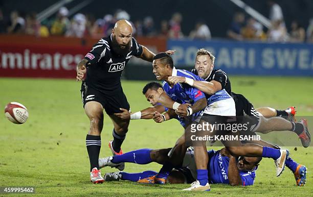 Forbes and Tim Mikkelson of New Zealand challenge Samoa's players during their rugby match on the first day of the Dubai leg of IRB's Sevens World...