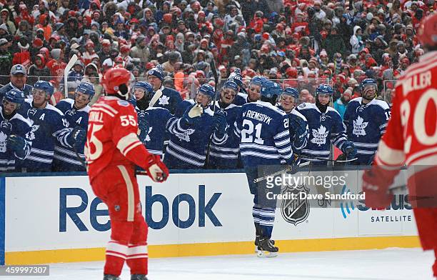 James van Riemsdyk of the Toronto Maple Leafs skates by the Leafs bench to celebrate his goal with teammates as Niklas Kronwall and Drew Miller of...