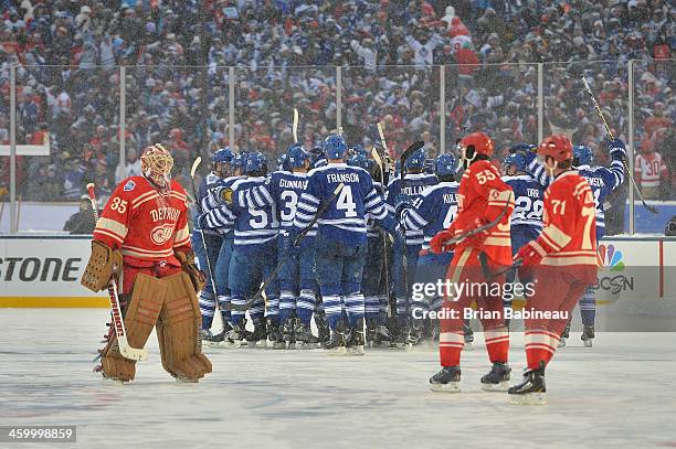 Goaltender Jimmy Howard of the Detroit Red Wings skates toward the Wings bench as teammates Niklas Kronwall and Daniel Cleary skate to meet Howard as...