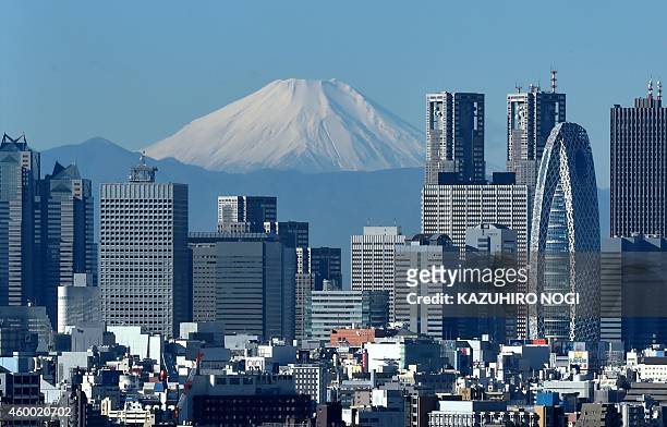 Japan's highest mountain, Mount Fuji is seen behind the skyline of the Shinjuku area of Tokyo on December 6, 2014. Tokyo stocks closed at a...