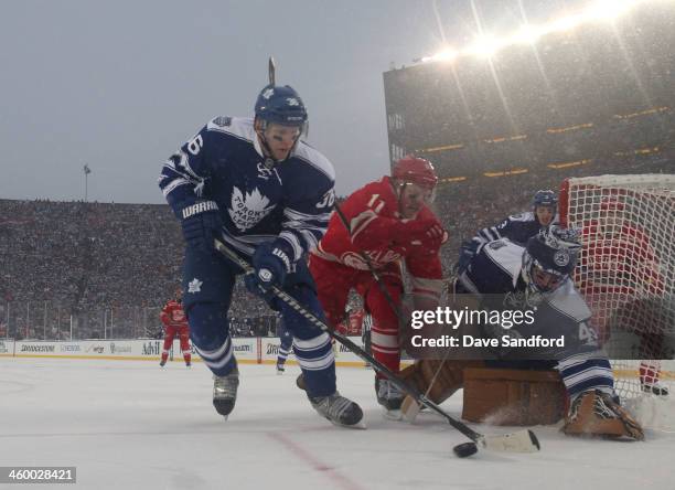 Carl Gunnarsson of the Toronto Maple Leafs controls the loose puck while under pressure from Daniel Alfredsson of the Detroit Red Wings as goaltender...