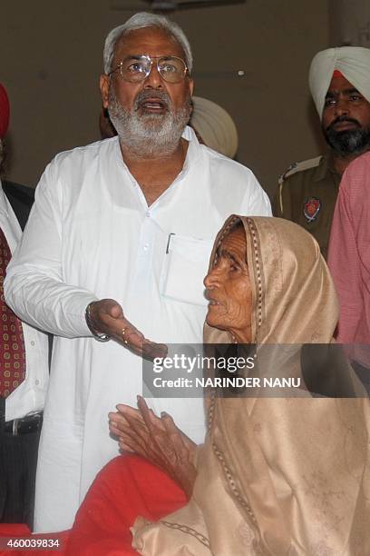 Indian Punjab state Health and Family Welfare Minister Surjit Kumar Jyani gestures to Pooro Kaur, who lost her eyesight after undergoing surgery, at...