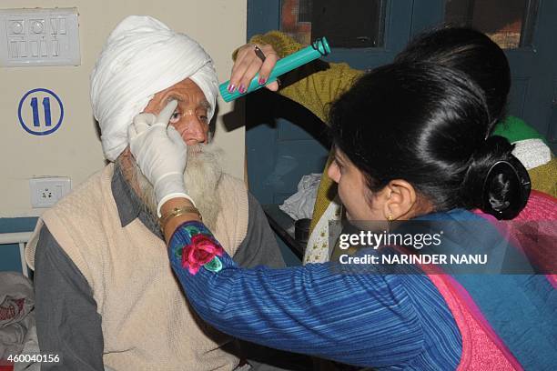 An Indian doctor inspects the eye of a patient, who lost his eyesight after undergoing free cataract surgery, at a government hospital in Amritsar on...