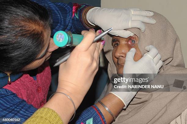 An Indian doctor inspects the eye of a patient, who lost her eyesight after undergoing free cataract surgery, at a government hospital in Amritsar on...