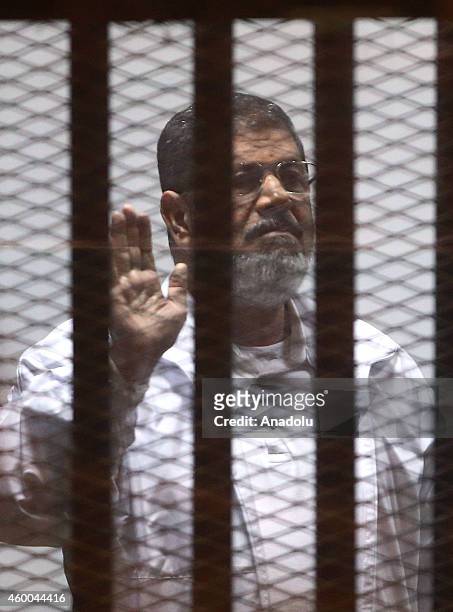 Mohamed Morsi stands inside a glass defendant's cage during his trial at Police Academy in the east of Cairo, Egypt, on December 6, 2014. Morsi and...