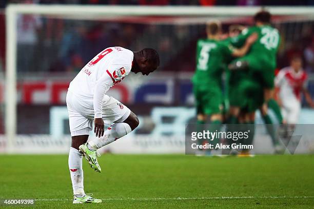 Anthony Ujah of Koeln reacts as Alexander Esswein of Augsburg celebrates his team's second goal with team mates during the Bundesliga match between...