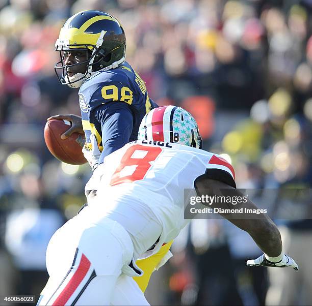 Quarterback Devin Gardner of the Michigan Wolverines throws a pass while avoiding pressure from defensive linemen Noah Spence of the Ohio State...