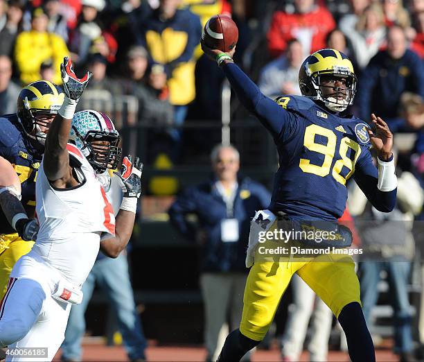 Quarterback Devin Gardner of the Michigan Wolverines throws a pass while avoiding pressure from defensive linemen Noah Spence of the Ohio State...