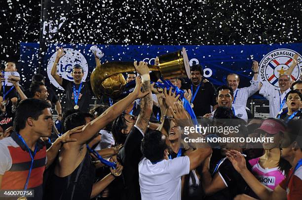 Libertad's players hold up the trophy after winning Paraguay's Clausura tournament final football match against Nacional, in Asuncion, on December 6,...