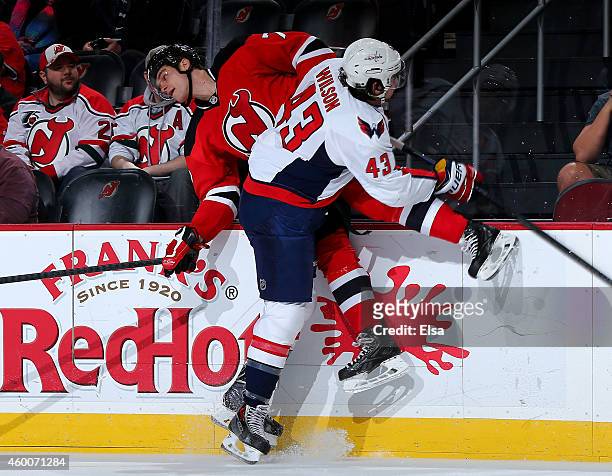 Tom Wilson of the Washington Capitals hits Jon Merrill of the New Jersey Devils in the first period on December 6, 2014 at the Prudential Center in...