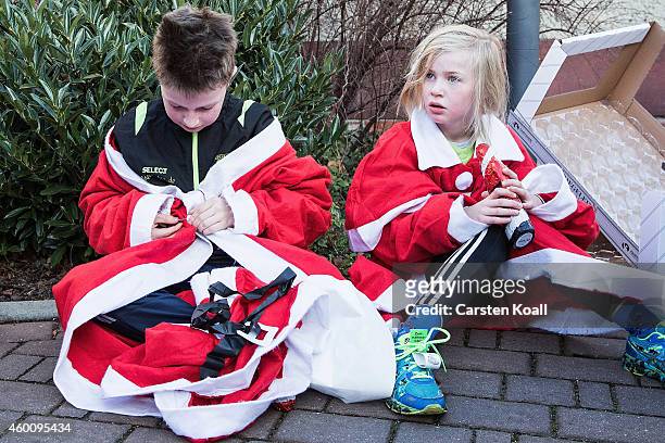 Two children dressed as Santa Claus rest after they took part the annual Santa Run on December 7, 2014 in Michendorf, Germany. At least 800 adults...